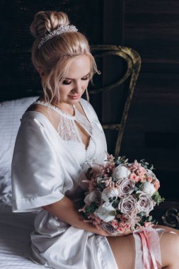 Güzel genç gelin düğün sabahı zarif iç kısımlarında çiçek buketi tutuyor.                      