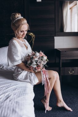 Güzel genç gelin düğün sabahı zarif iç kısımlarında çiçek buketi tutuyor.                      