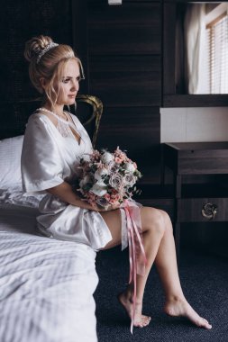 Güzel genç gelin düğün sabahı zarif iç kısımlarında çiçek buketi tutuyor.                      