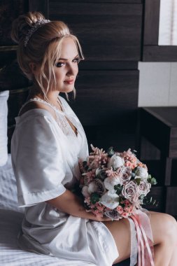 Güzel genç gelin düğün sabahı zarif iç kısımlarında çiçek buketi tutuyor.                      
