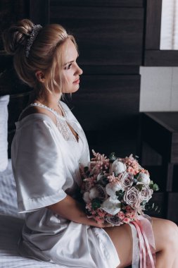 Güzel genç gelin düğün sabahı zarif iç kısımlarında çiçek buketi tutuyor.                      