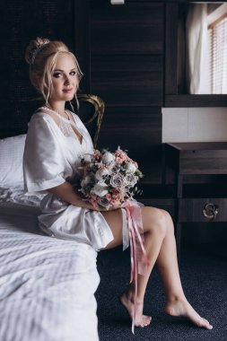 Güzel genç gelin düğün sabahı zarif iç kısımlarında çiçek buketi tutuyor.                      