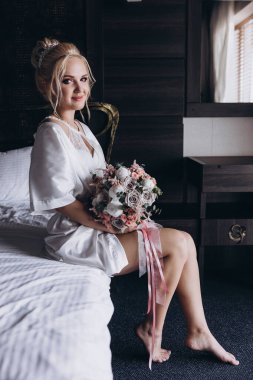 Güzel genç gelin düğün sabahı zarif iç kısımlarında çiçek buketi tutuyor.                      