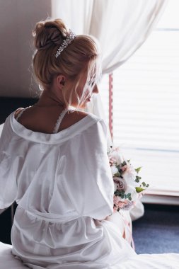 Güzel genç gelin düğün sabahı zarif iç kısımlarında çiçek buketi tutuyor.                      