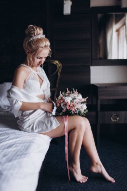 Güzel genç gelin düğün sabahı zarif iç kısımlarında çiçek buketi tutuyor.                      