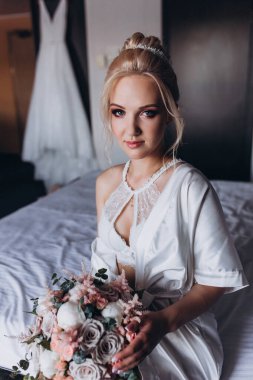 Güzel genç gelin düğün sabahı zarif iç kısımlarında çiçek buketi tutuyor.                      