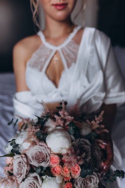 Güzel genç gelin düğün sabahı zarif iç kısımlarında çiçek buketi tutuyor.                      