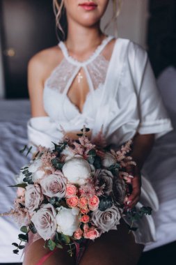 Güzel genç gelin düğün sabahı zarif iç kısımlarında çiçek buketi tutuyor.                      