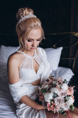 Güzel genç gelin düğün sabahı zarif iç kısımlarında çiçek buketi tutuyor.                      