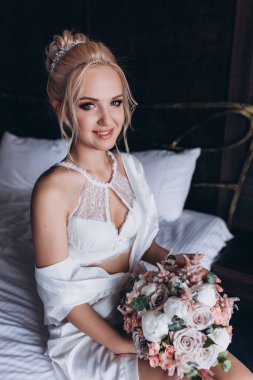 Güzel genç gelin düğün sabahı zarif iç kısımlarında çiçek buketi tutuyor.                      