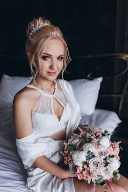 Güzel genç gelin düğün sabahı zarif iç kısımlarında çiçek buketi tutuyor.                      