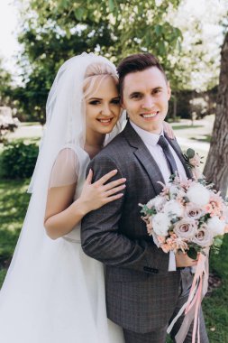 Güzel, mutlu, genç bir çift parkta birbirlerine sarılıp poz veriyorlar.                     