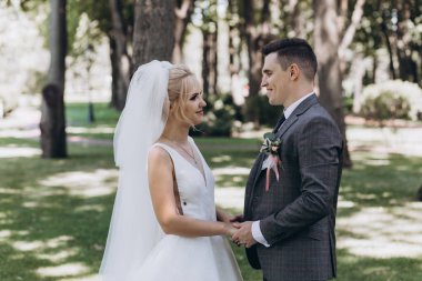 Güzel, mutlu, genç bir çift parkta el ele tutuşuyor.          