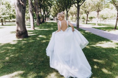 Park 'ta koşan gelinlikli güzel gelinin arka manzarası. 