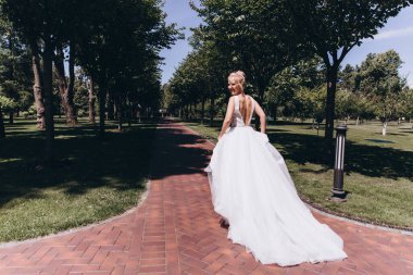 Park 'ta koşan gelinlikli güzel gelinin arka manzarası. 