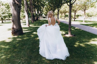Park 'ta koşan gelinlikli güzel gelinin arka manzarası. 