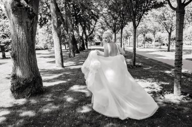 Park 'ta koşan gelinlikli güzel gelinin arka manzarası. 