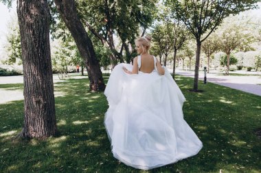Park 'ta koşan gelinlikli güzel gelinin arka manzarası. 