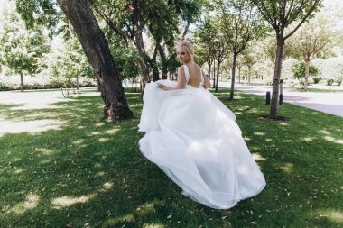 Park 'ta koşan gelinlikli güzel gelinin arka manzarası. 