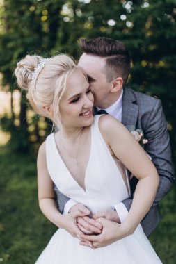 Güzel, mutlu, genç bir çift parkta birbirlerine sarılıp poz veriyorlar.                     