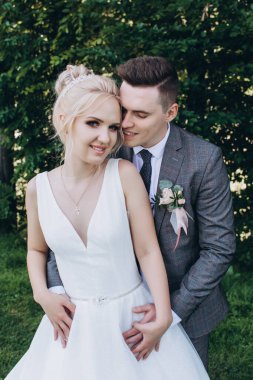 Güzel, mutlu, genç bir çift parkta birbirlerine sarılıp poz veriyorlar.                     