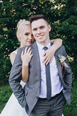 Güzel, mutlu, genç bir çift parkta birbirlerine sarılıp poz veriyorlar.                     