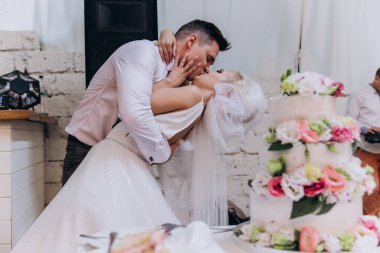 Mutlu genç gelin ve damat düğün günü evde öpüşüyor ve sarılıyorlar.       