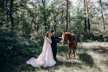 Ormanda atı olan mutlu gelin ve damat.               