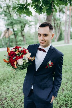 Elinde bir buket çiçek tutan yakışıklı damat.