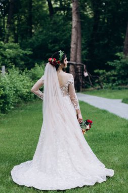 Yeşil yaz parkında poz veren güzel gelinin portresi.            