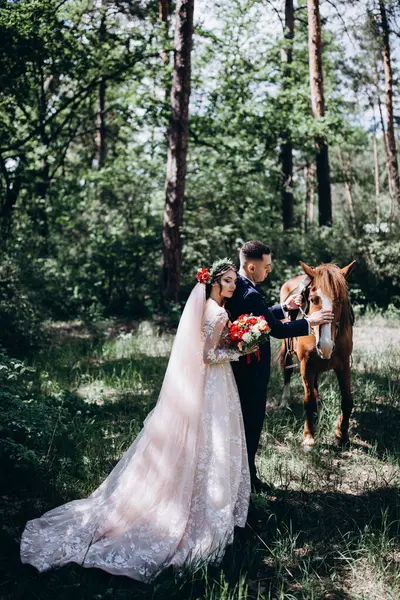 Ormanda atı olan mutlu gelin ve damat.               
