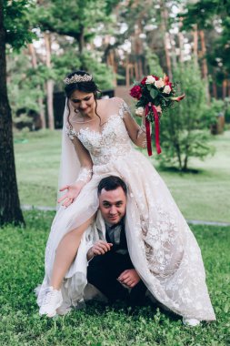 Mutlu genç gelin ve damat parkta eğleniyor ve sırtına biniyor.        
