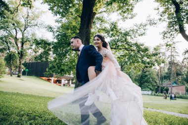 Mutlu genç gelin ve damat parkta eğleniyor ve sırtına biniyor.        