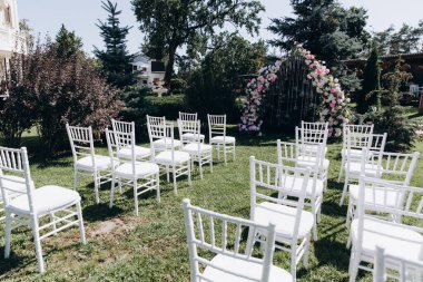 Çiçekli kemer ve sandalyeli bahçede düğün töreni. 