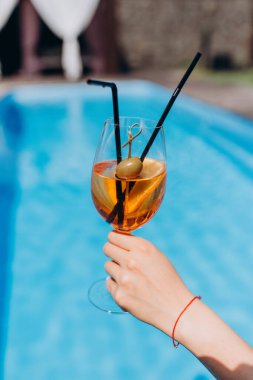 Havuzun yanında kokteyl içen bir kadın eli. yaz tatili konsepti