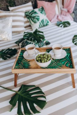 Kahvaltınız, kahve ve üzüm dolu yeşil yapraklı, ahşap tepside.   