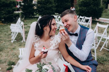 Mutlu genç gelin ve damat çifti lezzetli kekler yiyor.        