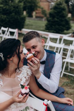 Mutlu genç gelin ve damat çifti lezzetli kekler yiyor.        