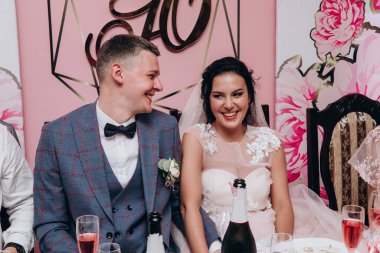 Genç gelin ve damat restoranda gülüyor.