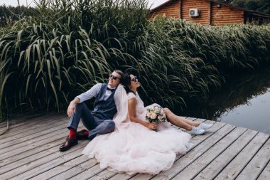 Mutlu gelin ve damat göldeki ahşap iskelede poz veriyor.               