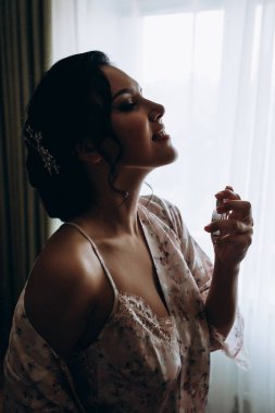 Genç ve güzel bir gelin sabahları elinde parfüm şişesi tutuyor.
