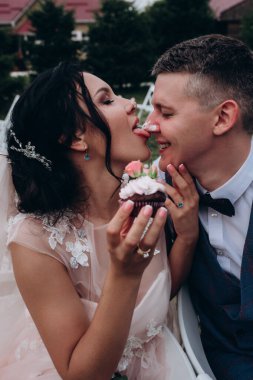 Mutlu genç gelin ve damat çifti lezzetli kekler yiyor.        