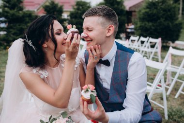 Mutlu genç gelin ve damat çifti lezzetli kekler yiyor.        