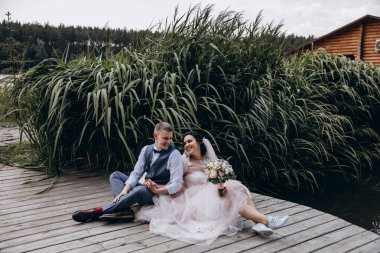 Mutlu gelin ve damat göldeki ahşap iskelede poz veriyor.               