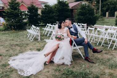 Düğün çifti sandalyede öpüşüyor. 