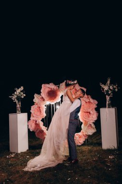 Gelin ve damat gece çiçek kemerine karşı 