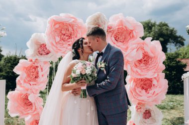 Çiçek kemerine karşı poz veren güzel bir çift. 