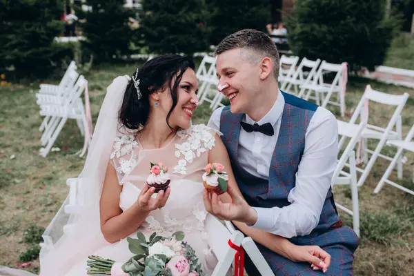 Mutlu genç gelin ve damat çifti lezzetli kekler yiyor.        