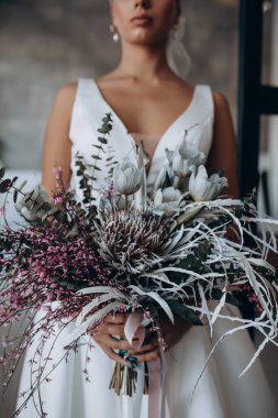 Çekici genç gelinin portresi güzel bir düğün buketi tutuyor.               