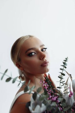 Çekici genç gelinin portresi güzel bir düğün buketi tutuyor.               